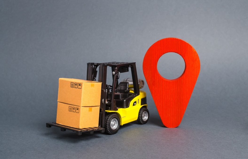 a forklift with boxes next to a location pinpoint to show the idea of moving your business from one place to another and the difficulties within that
